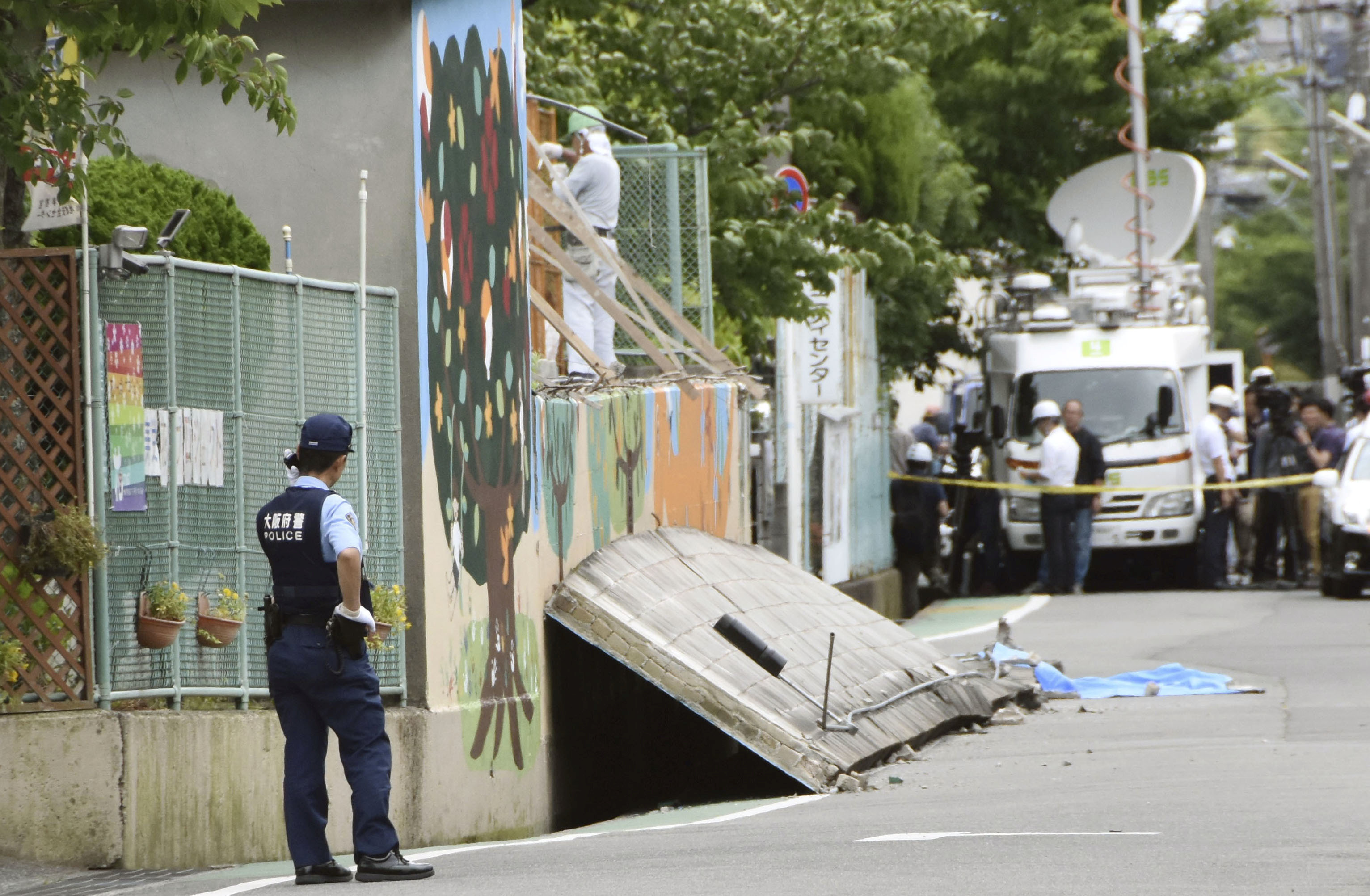 	ضابط يابانى يتابع الموقف بعد سقوط حائط على فتاة أدى إلى وفاتها