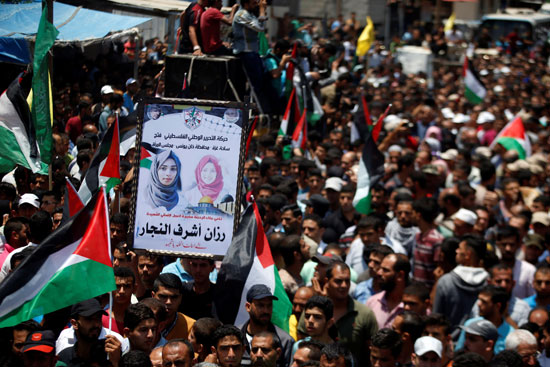 فلسطينيون يرفعون صور الشهيدة رزان النجار خلال جنازتها