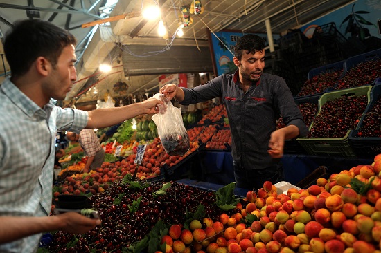 بائع فاكهة فى أحد أسواق تركيا يحاول إقناع الزبون باقتناء المزيد