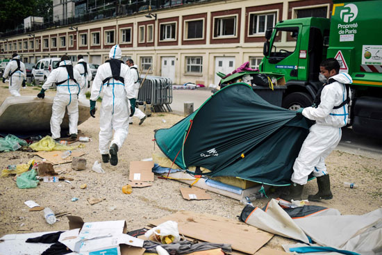 رفع مخلفات مخيم للمهاجرين على سيارات القمامة فى باريس