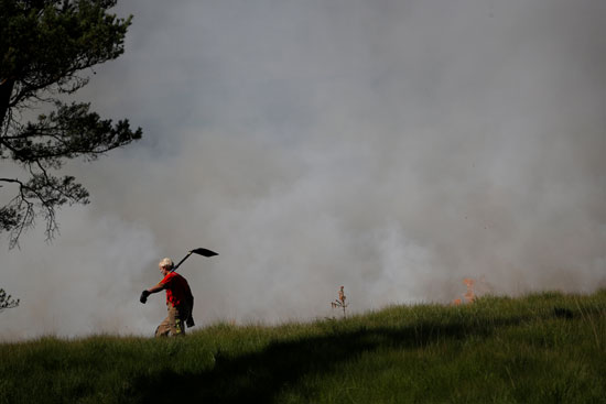 رجل إطفاء يحمل مجرفة أثناء مواجهة حريق فى بريطانيا