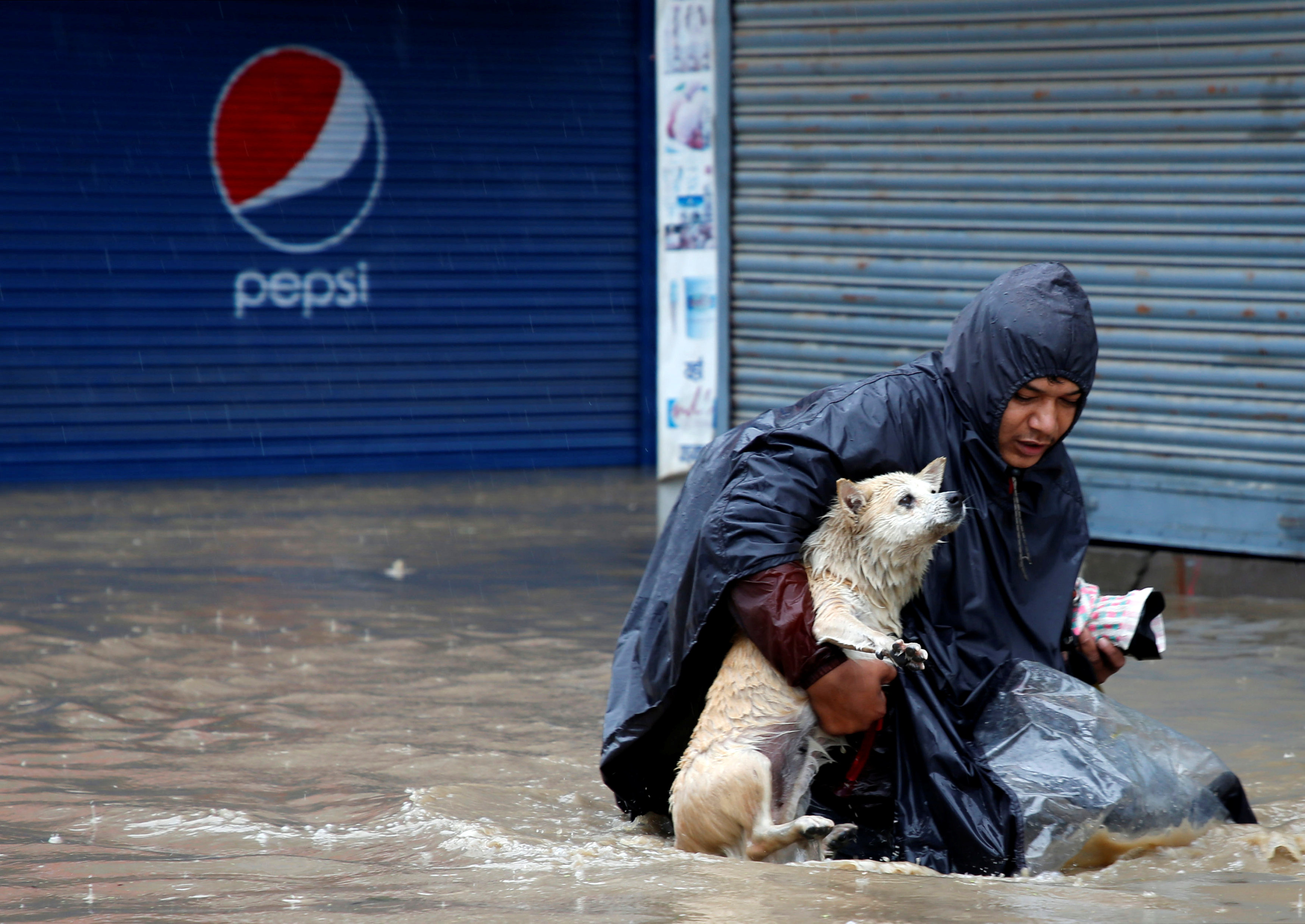 مواطن يحاول إنقاذ كلبه من الفيضانات