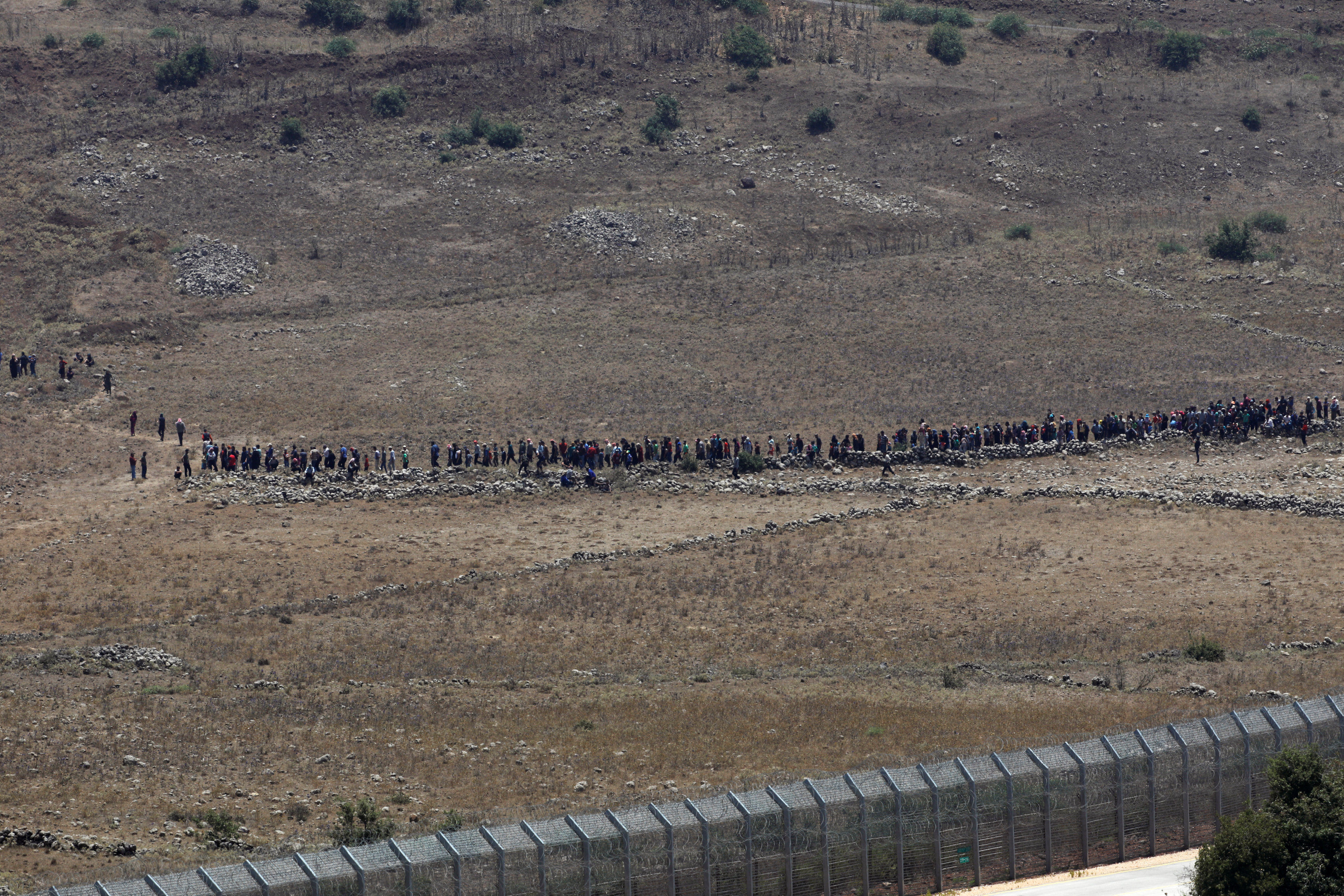 عشرات المدنيين السوريين أثناء مسيرتهم نحو الحدود مع إسرائيل