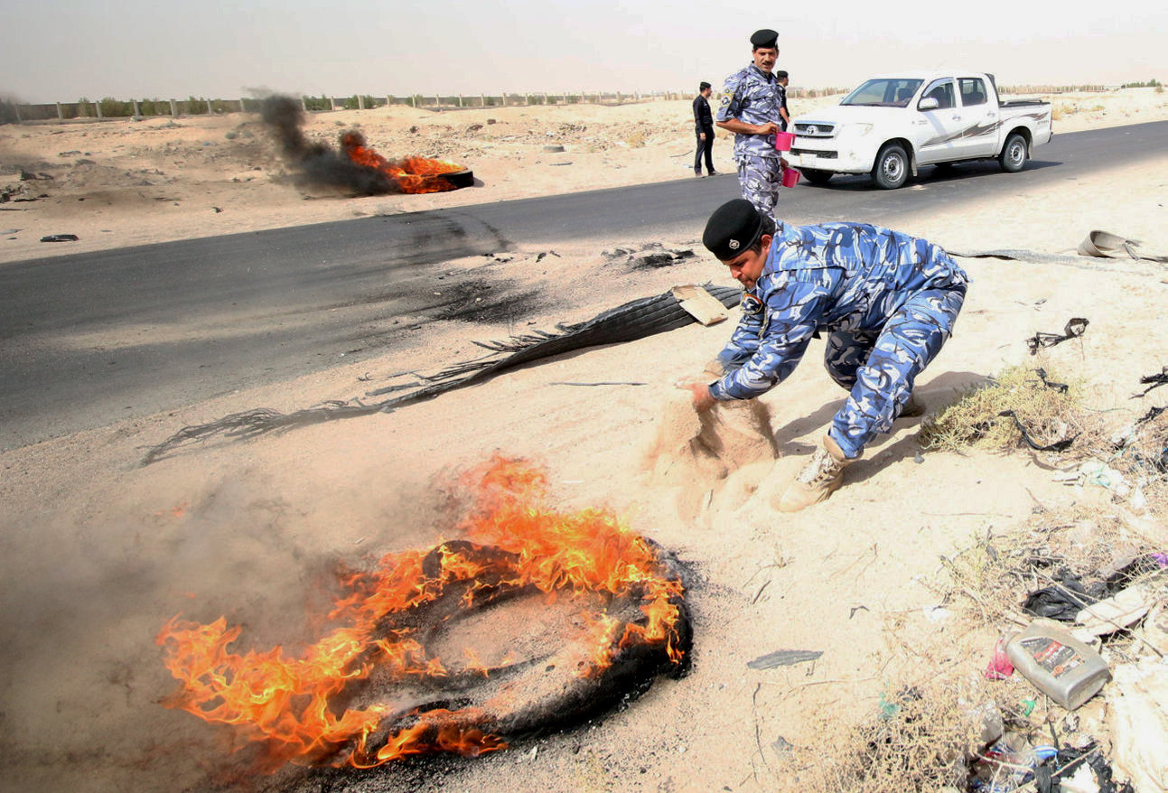 جندى عراقى يحاول إطفاء أحد الإطارات المحترقة
