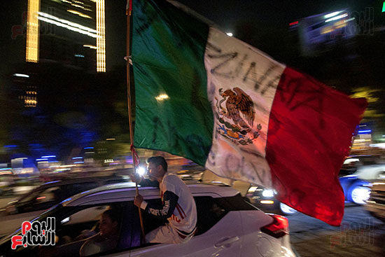 أحد المكسيكيين يرفع علم بلاده احتفالا بالرئيس الجديد