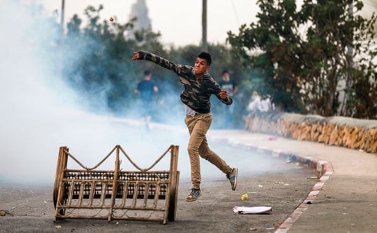 فلسطينى يضرب قوات الاحتلال بالحجارة