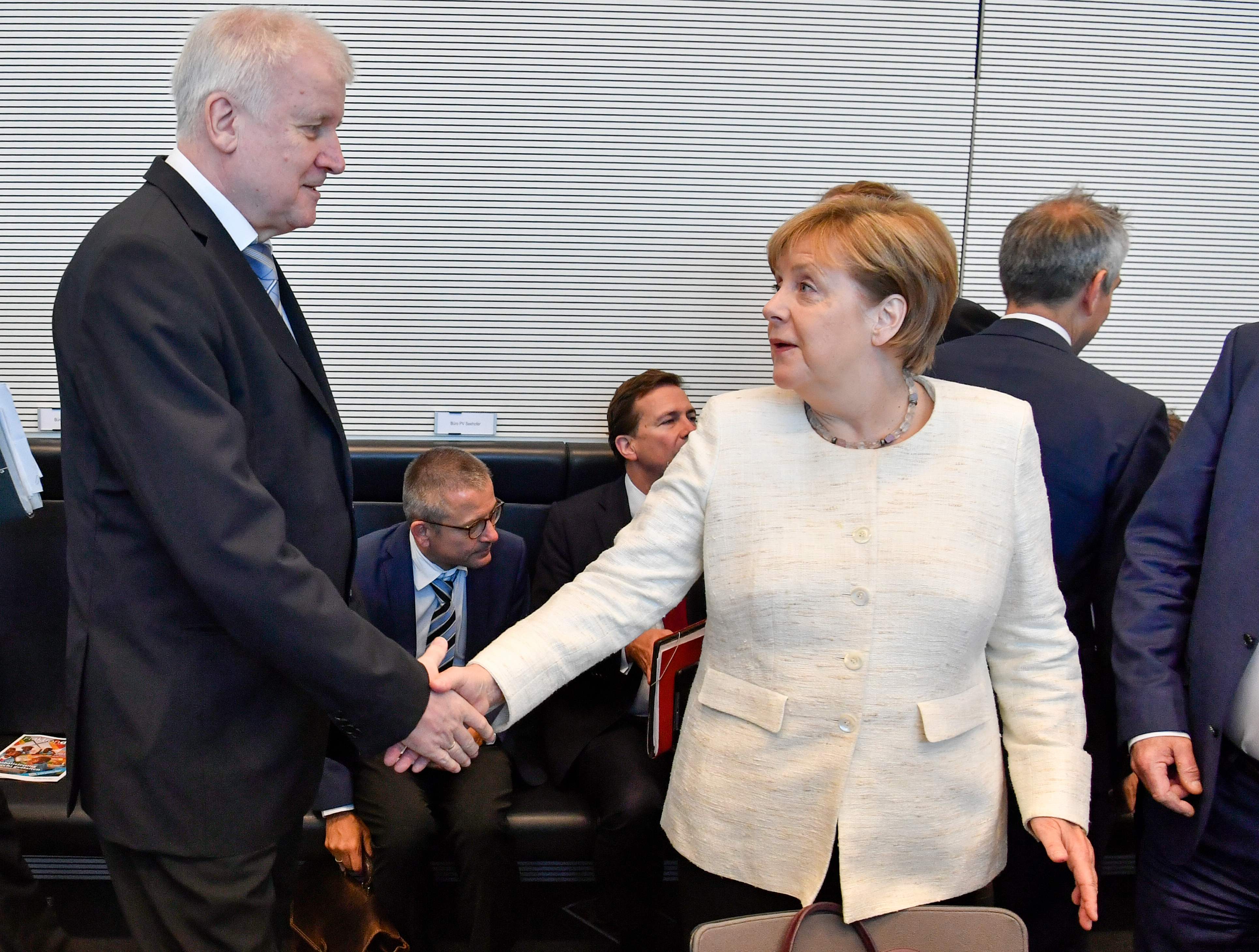 ميركل تصافح وزير الداخلية الألمانى فى أول لقاء عقب انتهاء الأزمة