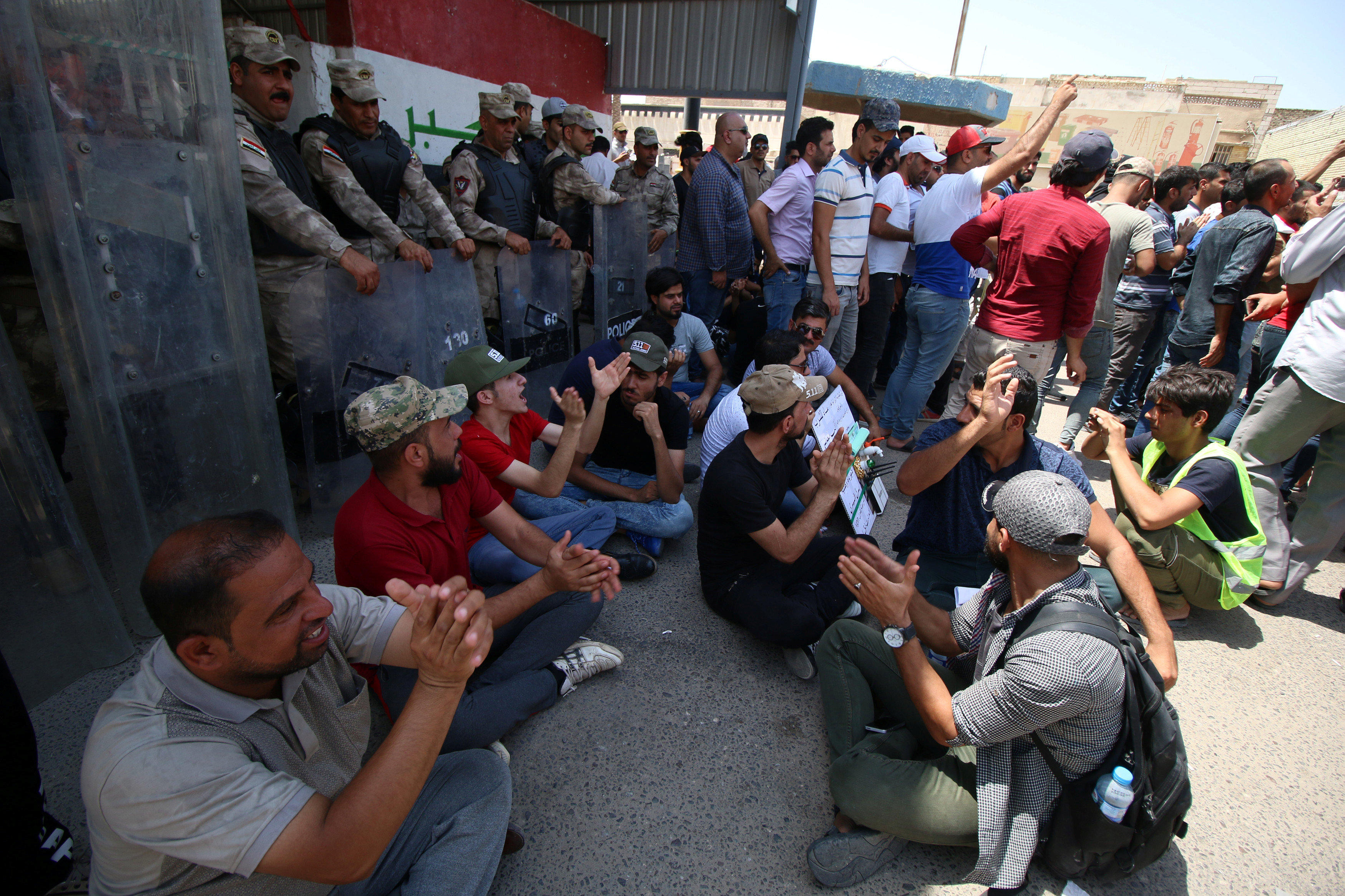 متظاهرون يجلسون أمام قوات الأمن