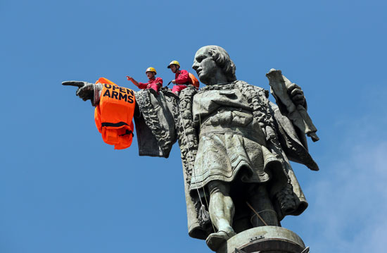 نشطاء يرتدون ملابس العوم بينما يقفون على تمثال كريستوفر كولومبوس ببرشلونة