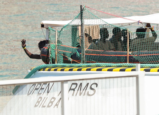 أحد المهاجرين يلوح بيده من السفينة