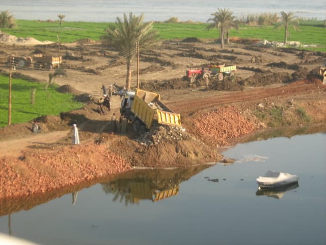 سيارات محملة بالرمال تقوم بردم نهر لنيل فى البدرشين بالجيزة
