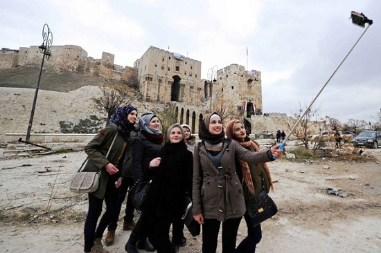 سياح أتراك يلتقطون سيلفى فى حلب مع آثار الحرب