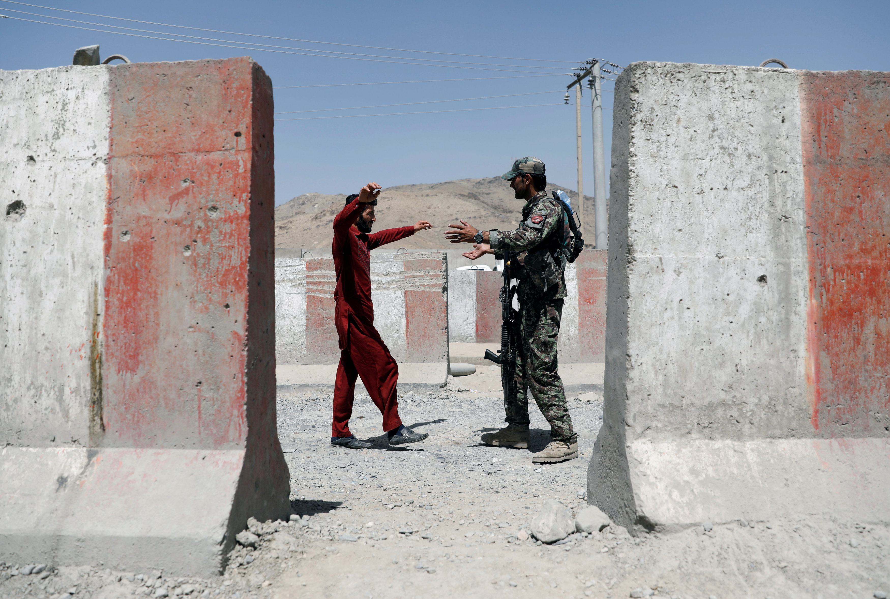 	جندي من الجيش الأفغانى يتفقد أحد الركاب عند نقطة تفتيش فى غزنة 