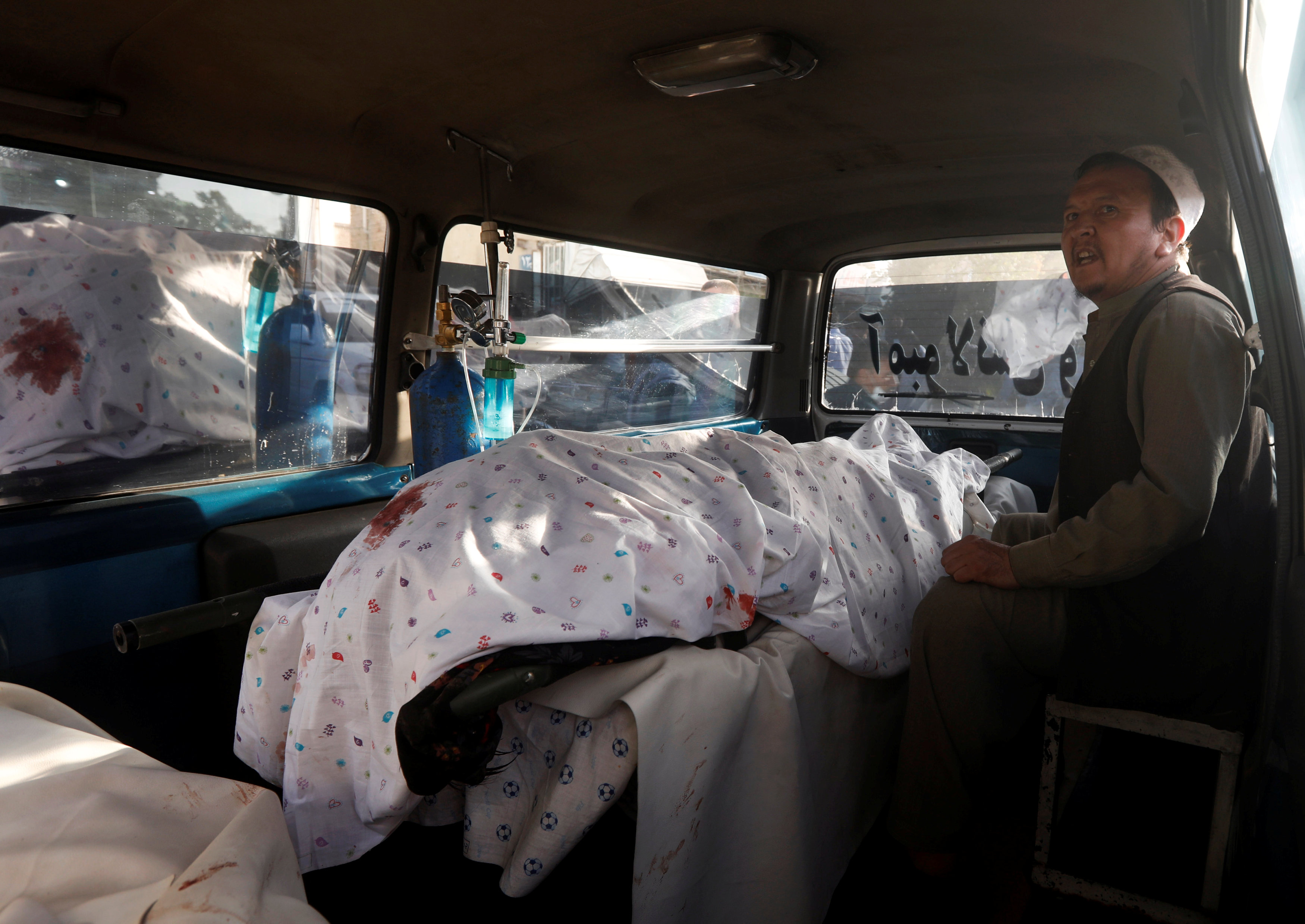 رجل أفغاني يجلس بجوار جثة أحد ذويه داخل سيارة إسعاف فى انفجار كابول