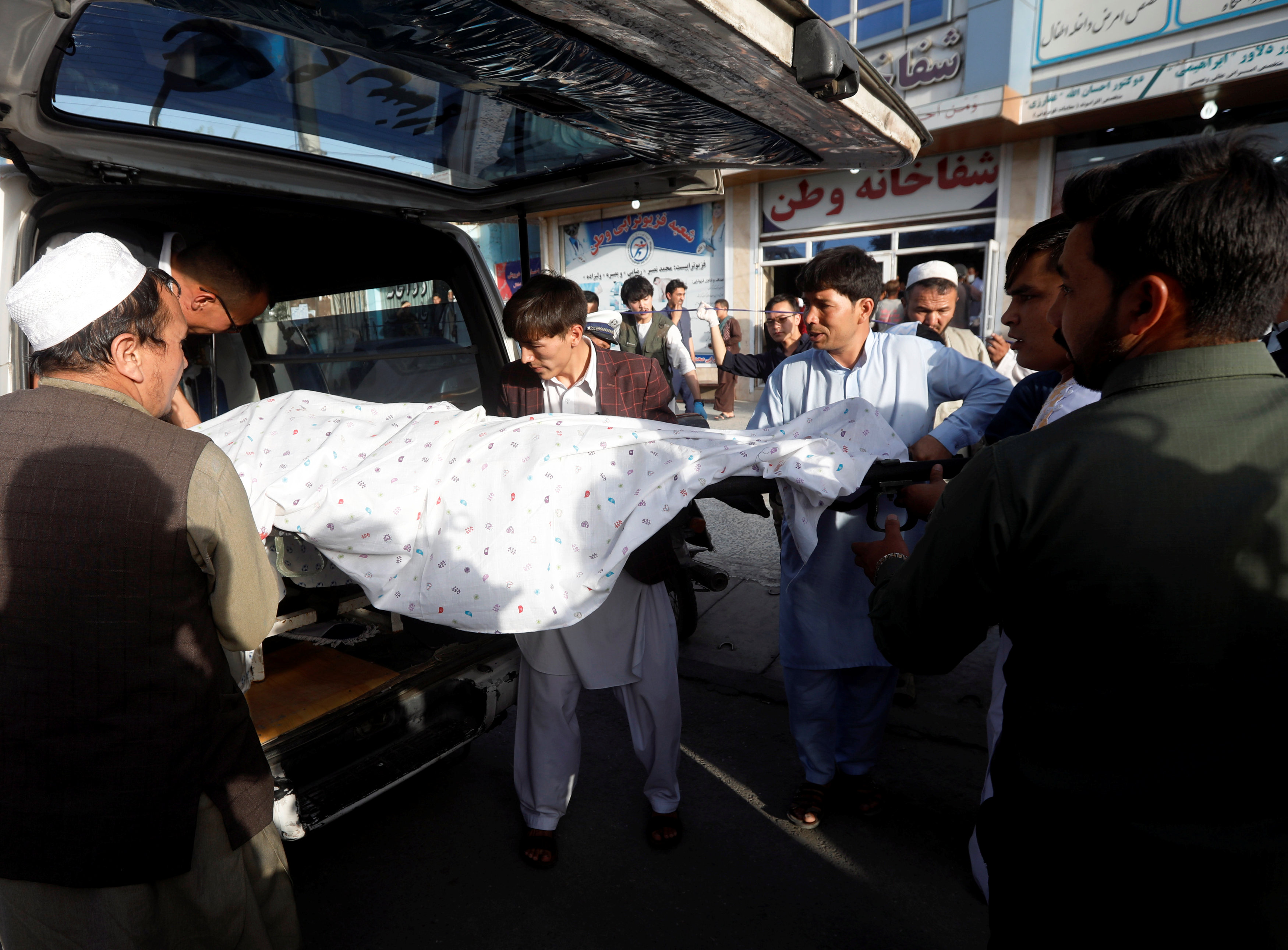 يحمل الرجال الأفغان جثة ضحية داخل سيارة إسعاف بالقرب من موقع التفجير