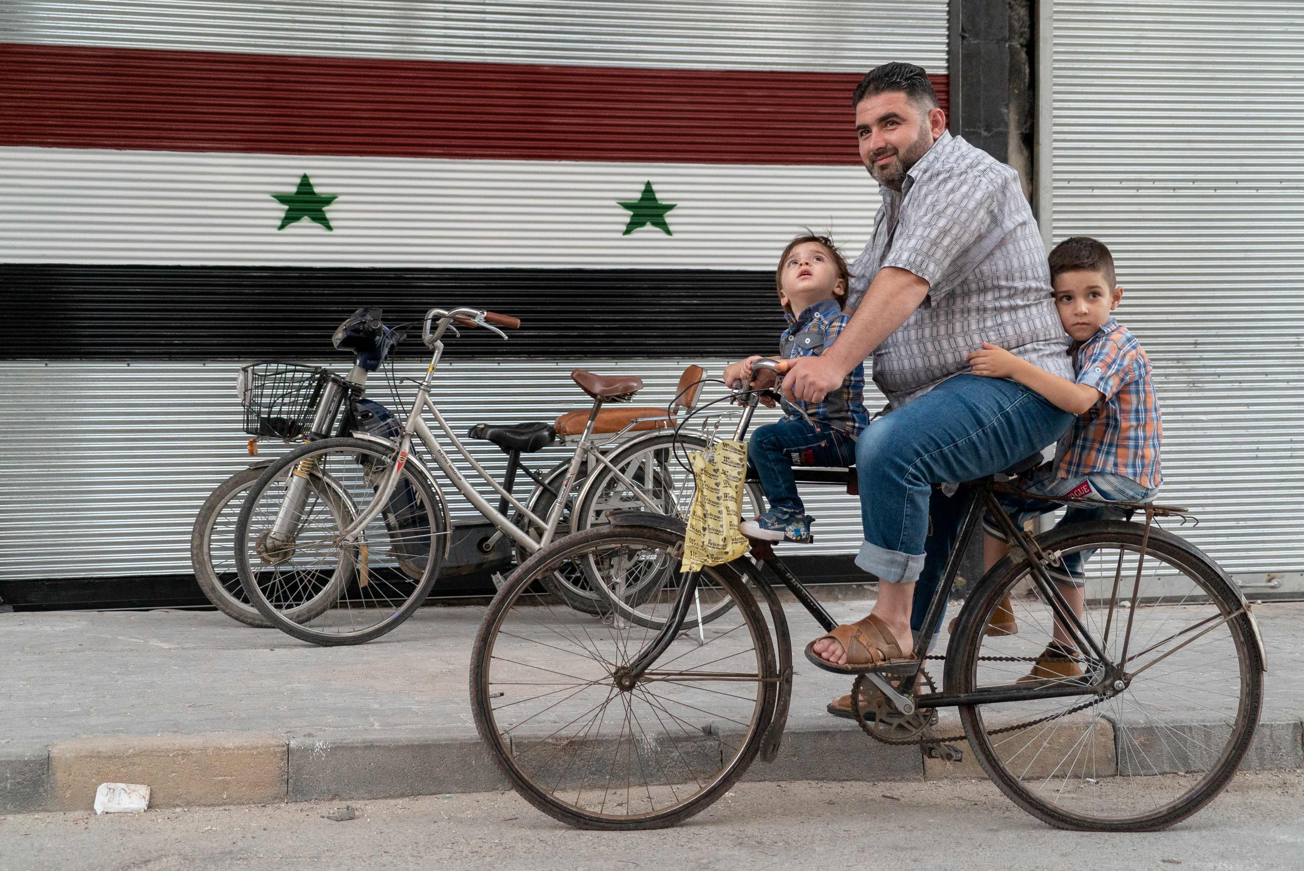 سورى بصحبة ابناءه على دراجه فى سوريا يشعر بالآمان
