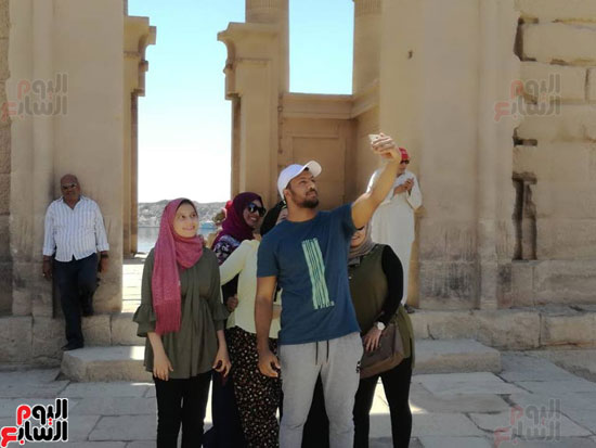 عدد من الزائرين المصريين يلتقطون الصور التذكارية بالمعبد
