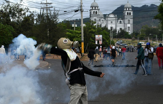 أحد المتظاهرين يمسك بقنبلة غاز