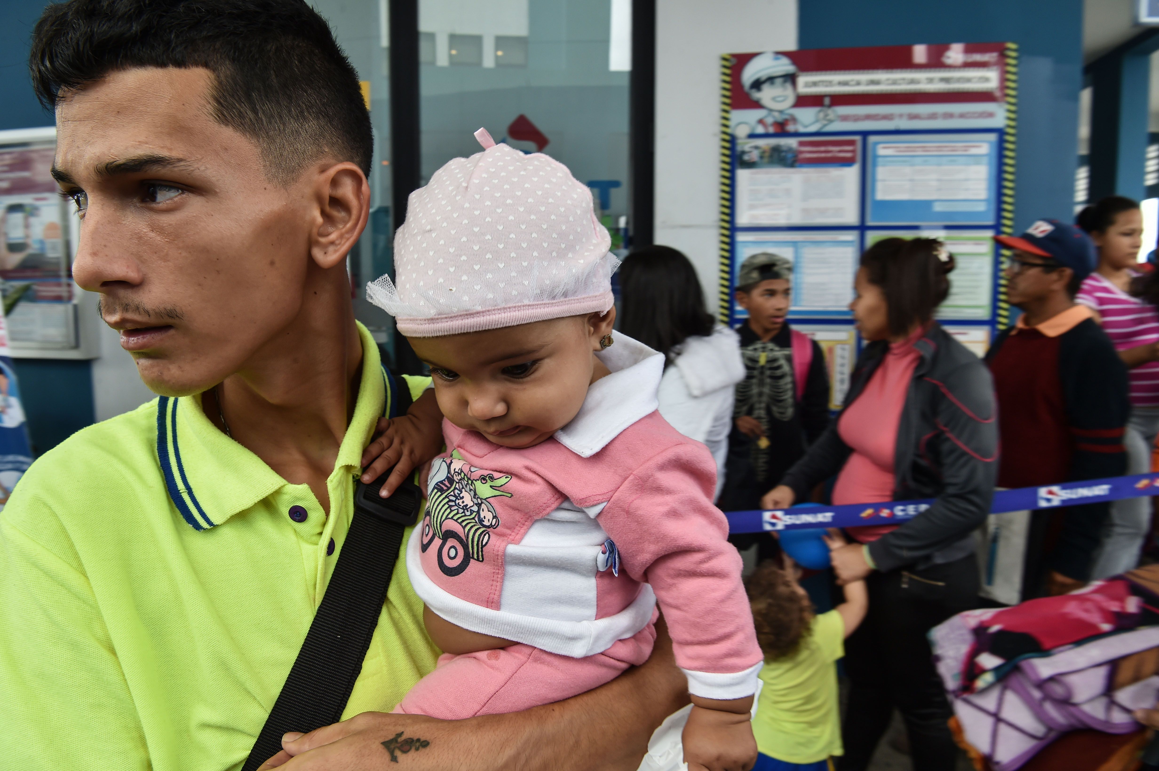 رجل يحمل طفله عقب وصوله بيرو