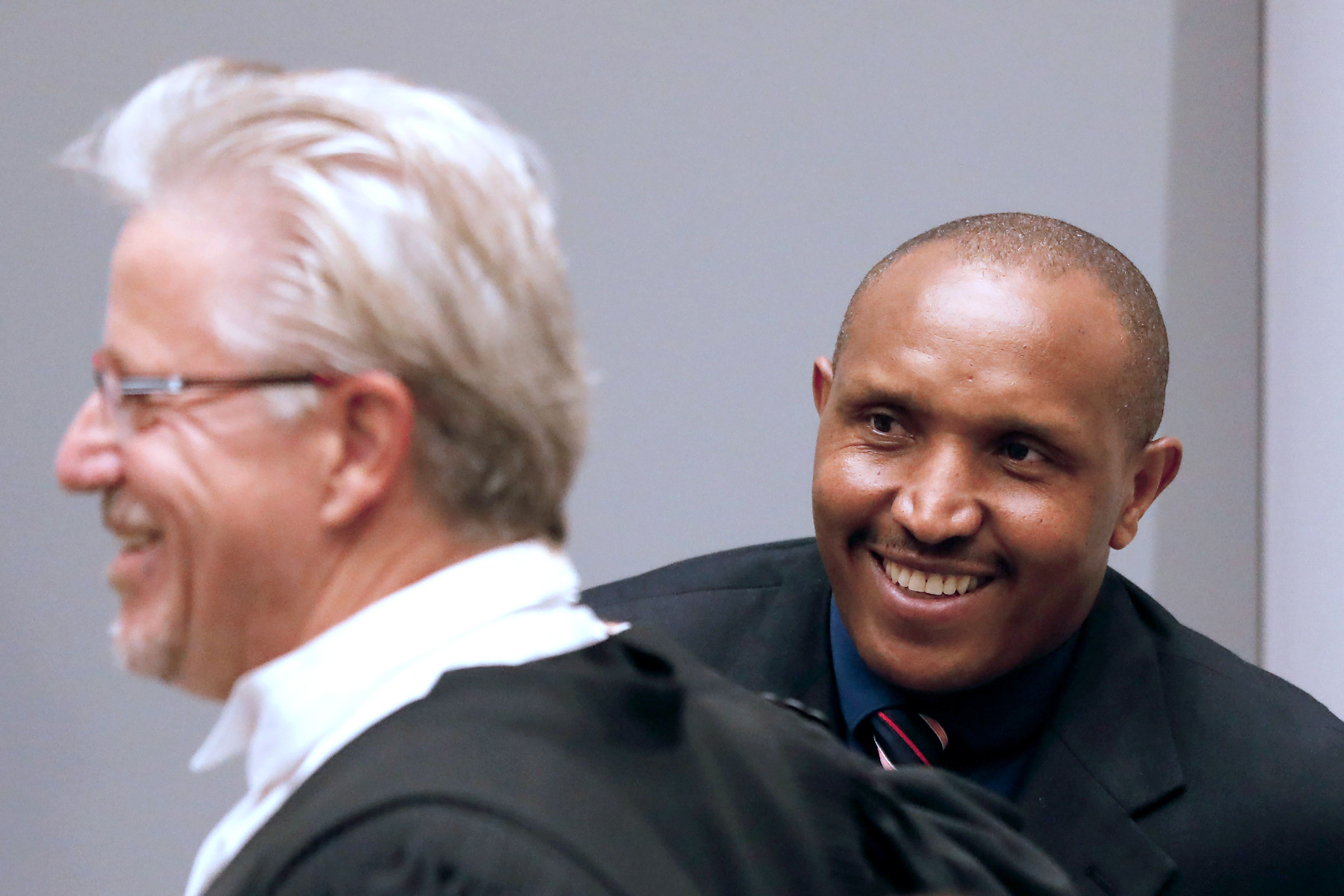 المتهم مبتسما أثناء جلسة محاكمته بحضور محاميه