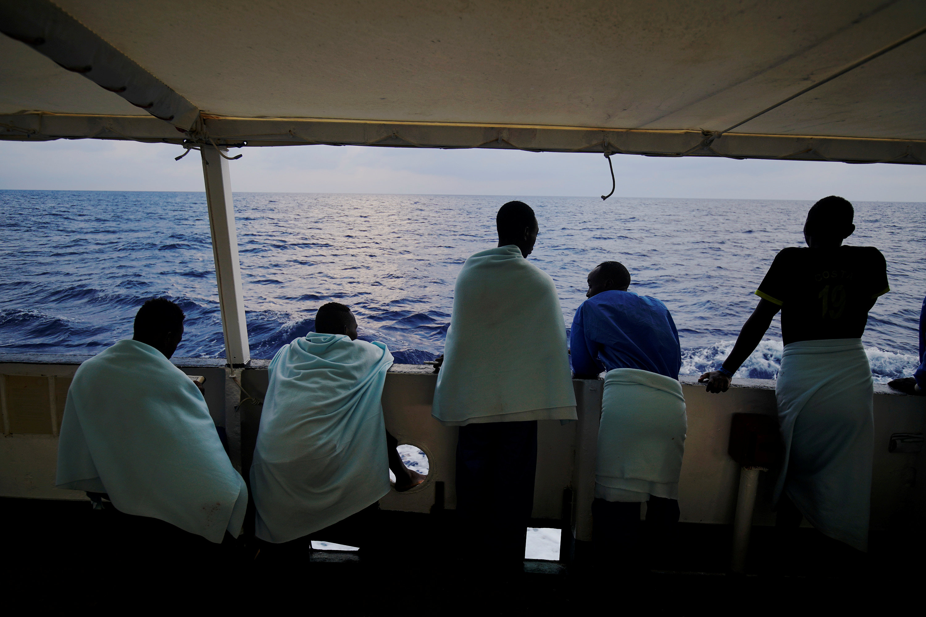 المهاجرون يقفون على متن سفينة الإنقاذ التابعة لمنظمة غير حكومية