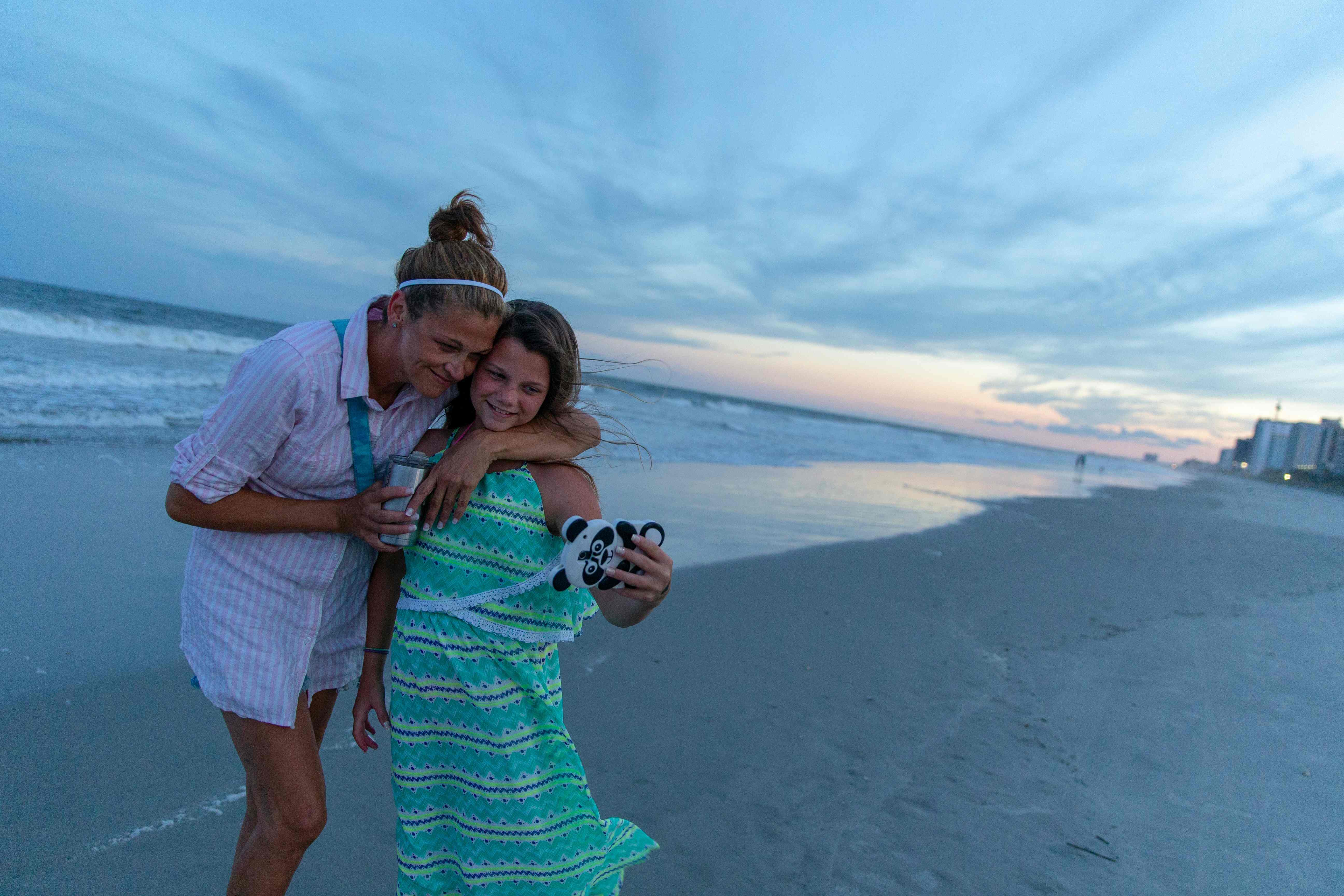 فتاة تلتقط صورة شخصية مع والدتها أثناء غروب الشمس فى ميرتل بيتش جنوب كارولينا