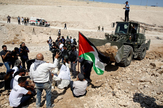 الفلسطينيون يرفعون علم بلادهم أمام جرافات الاحتلال الإسرائيلى 