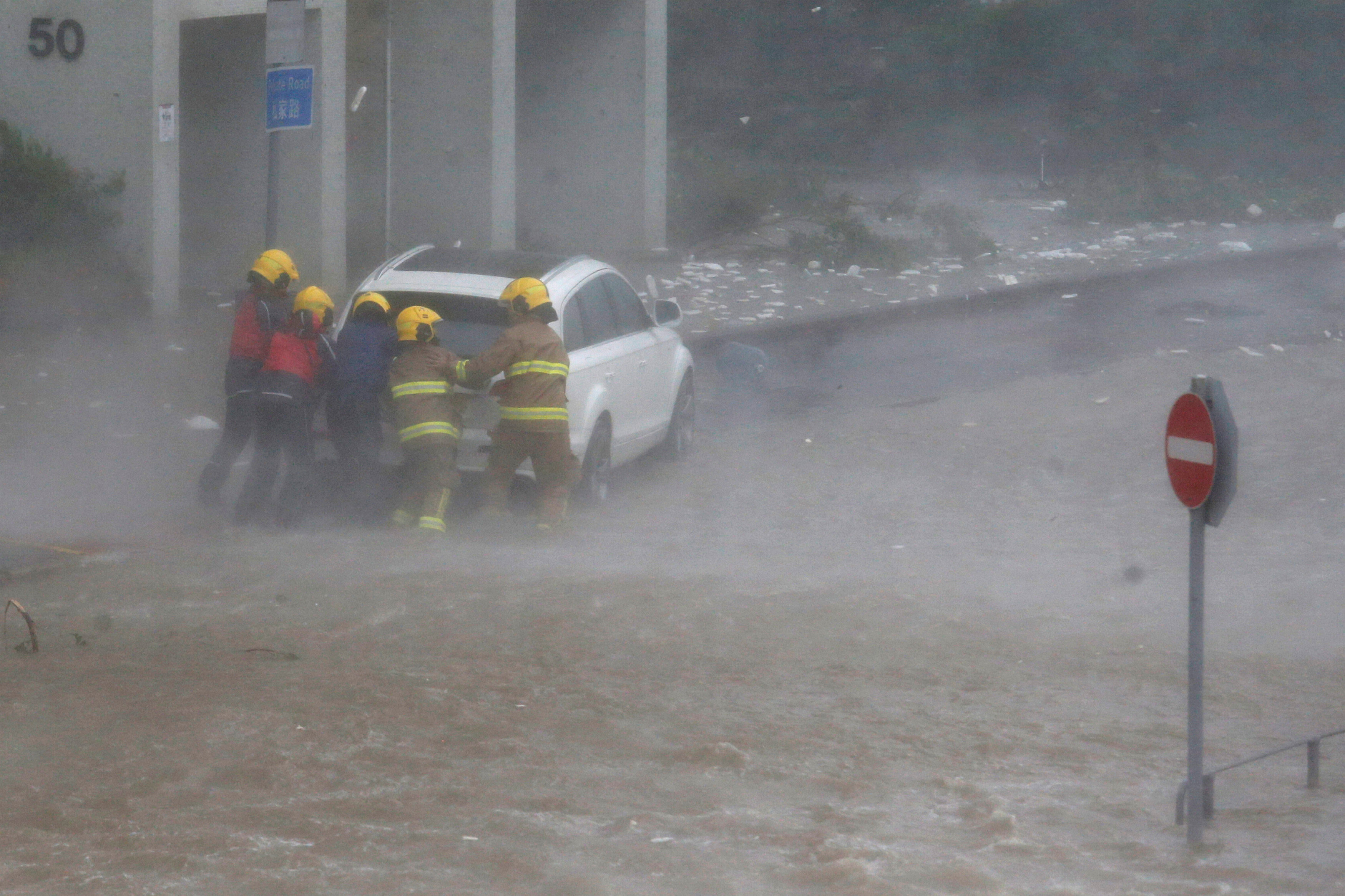 رجال الإنقاذ يحاولون التعامل مع سيارة توقفت بسبب الإعصار