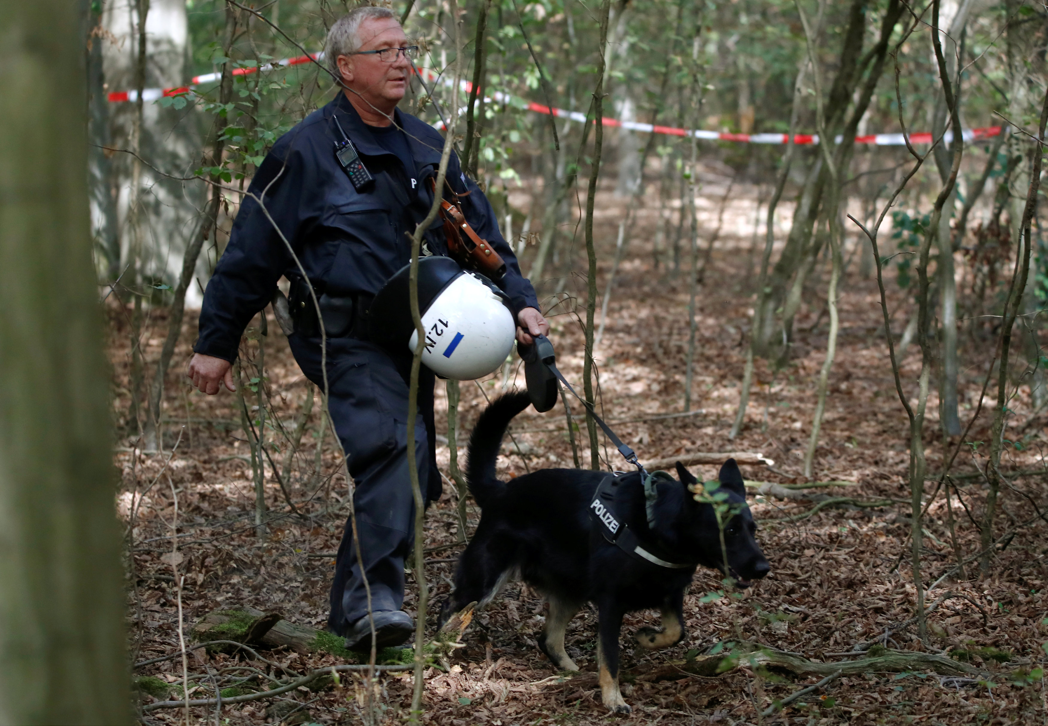 أحد أفراد الشرطة الألمانية يتجول بصحبة كلب بوليسى لتمشيط الغابة