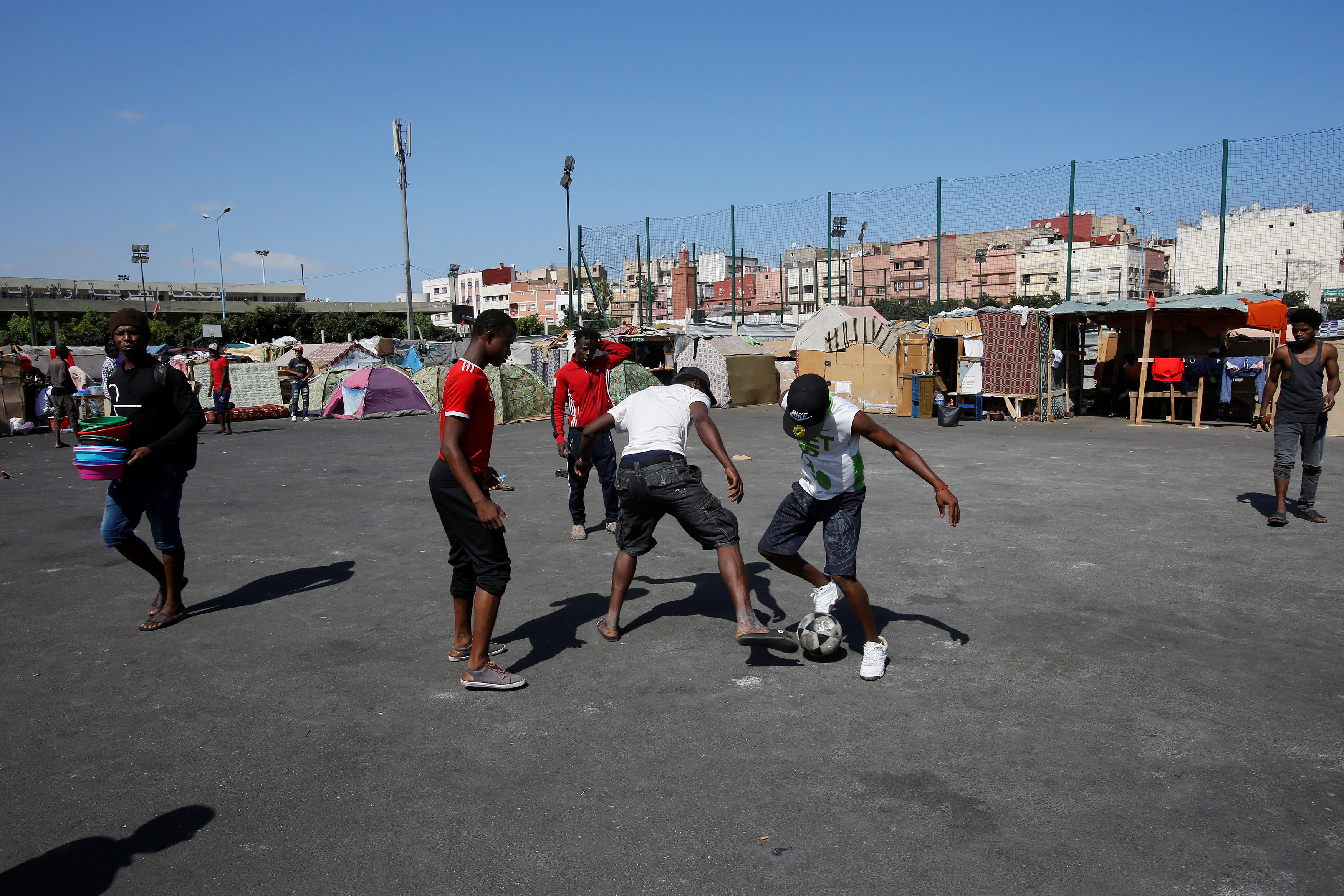 بعض المهاجرين يلعب كرة قدم فى الشارع