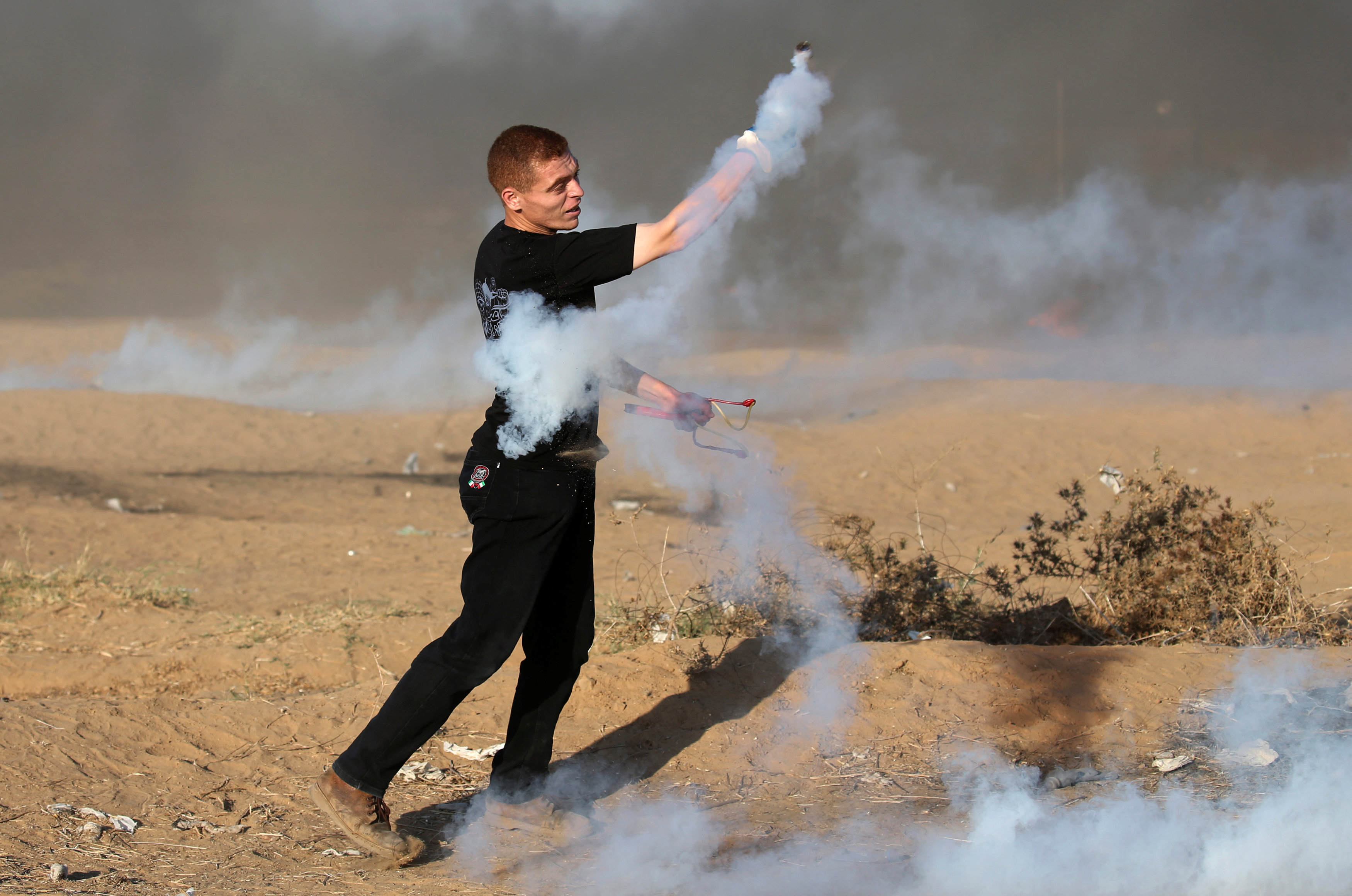فلسطينى يحمل قنبلة غاز بعد إطلاقها من قوات الاحتلال