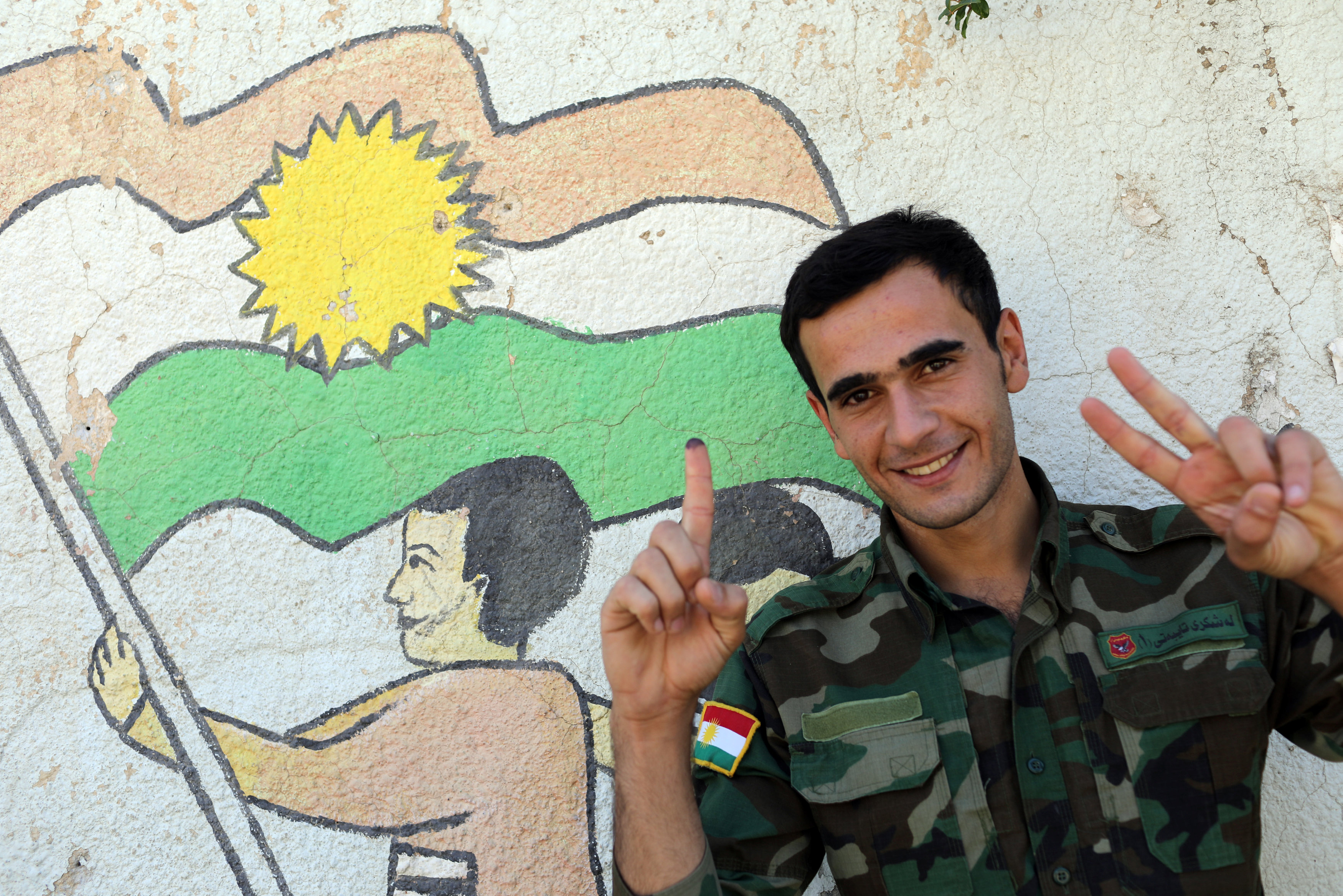 أحد أفراد القوات العسكرية الكردية إصبعه بالحبر بعد الإدلاء بصوته في مركز اقتراع فى منطقة شبه الحكم بأربيل