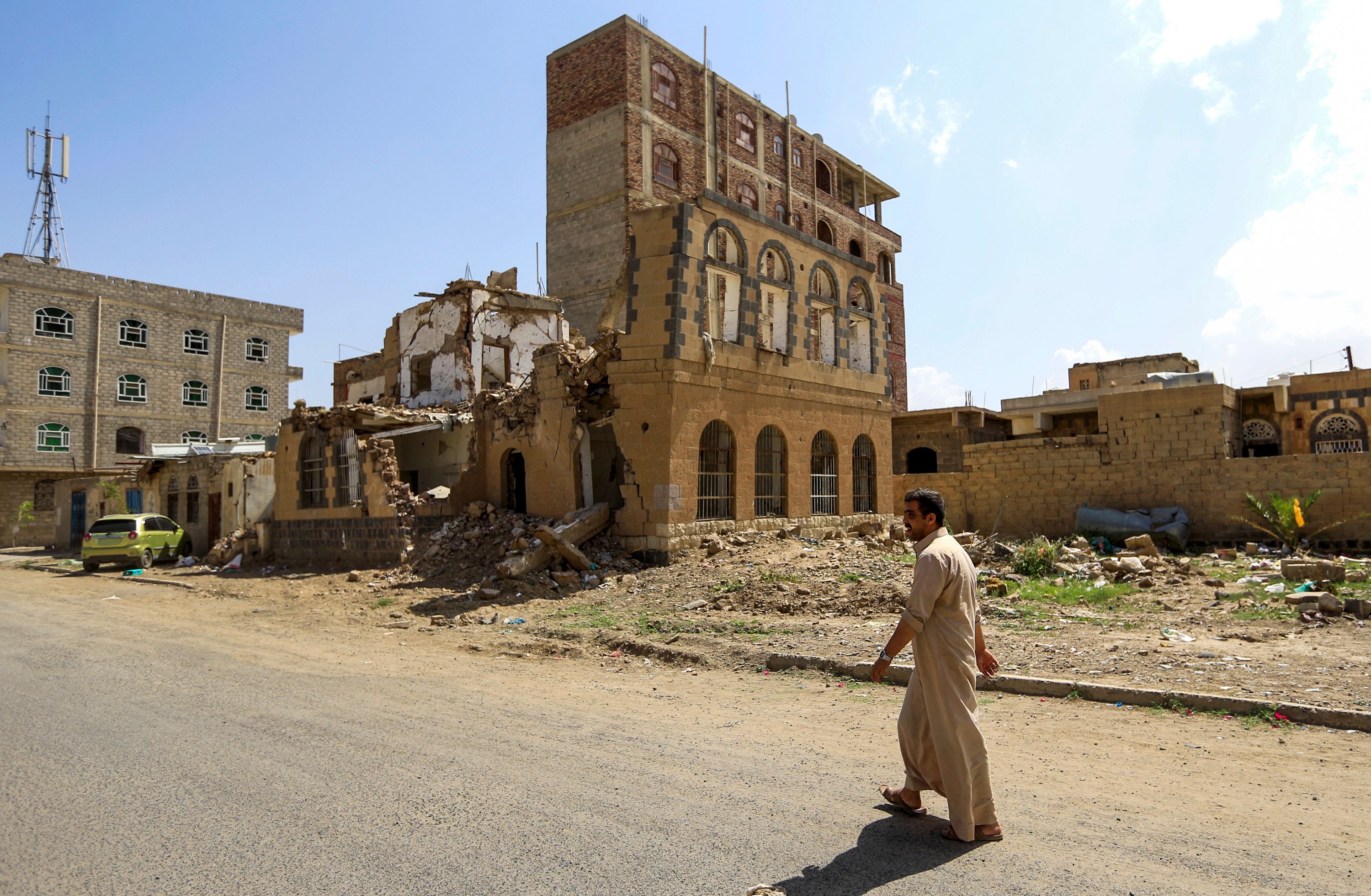 رجل يمني يمر عبر حطام مبنى تم تدميره فى غارة جوية