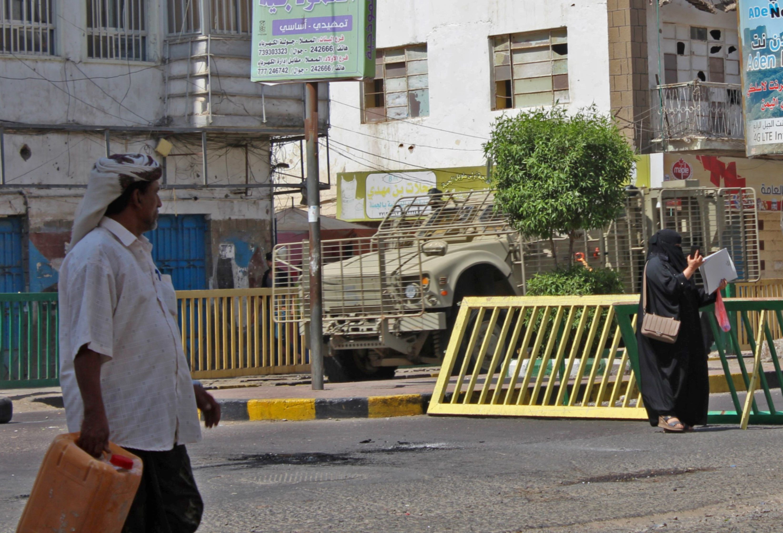 رجل يمنى وسيدة يمران أمام حاجز أمنى فى مدينة عدن