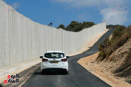	احدى السيارات تسير بطول الجدار الفاصل بعد رصف الطريق