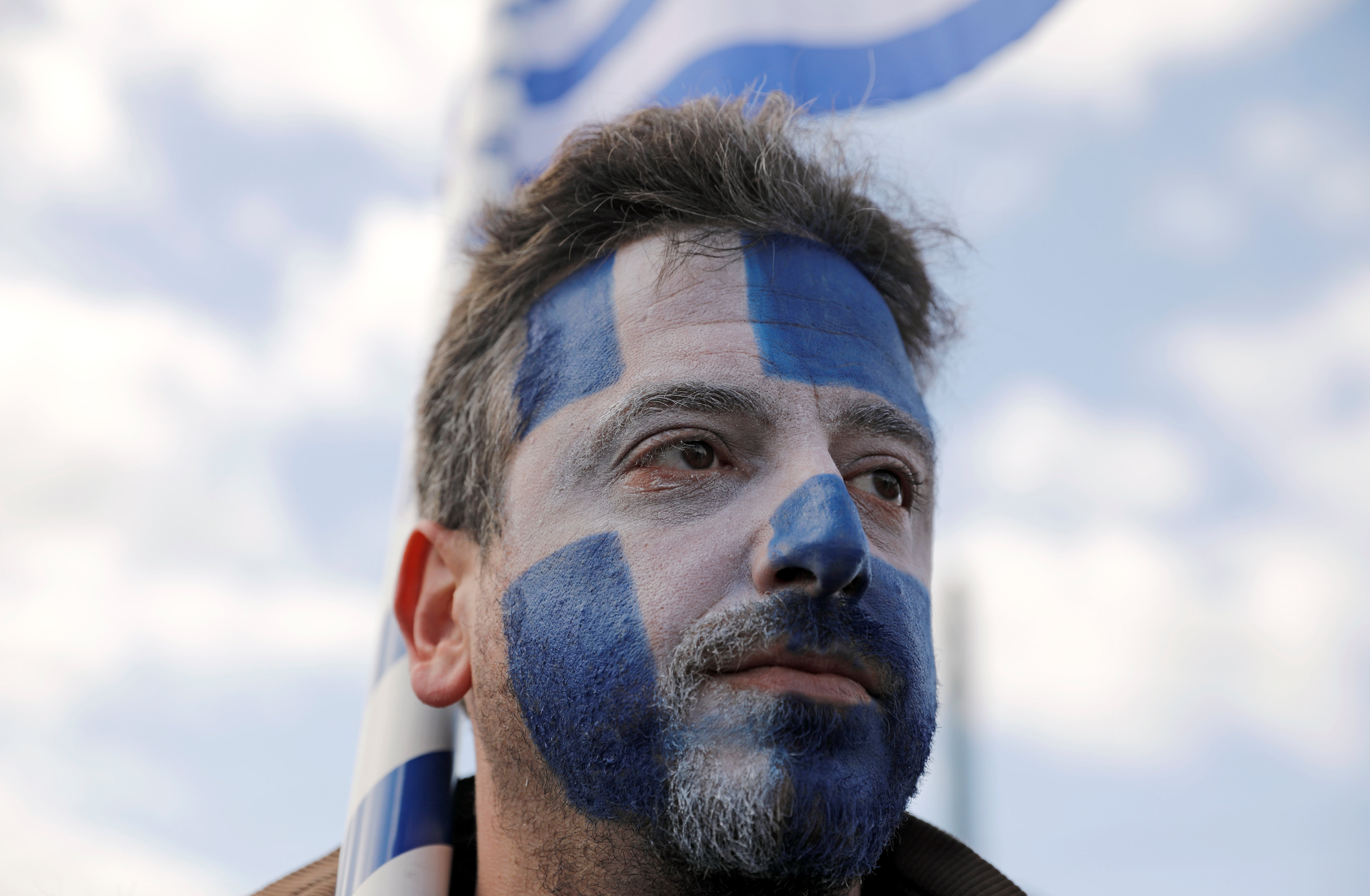أحد المتظاهرين يرسم علم اليونان على وجهه