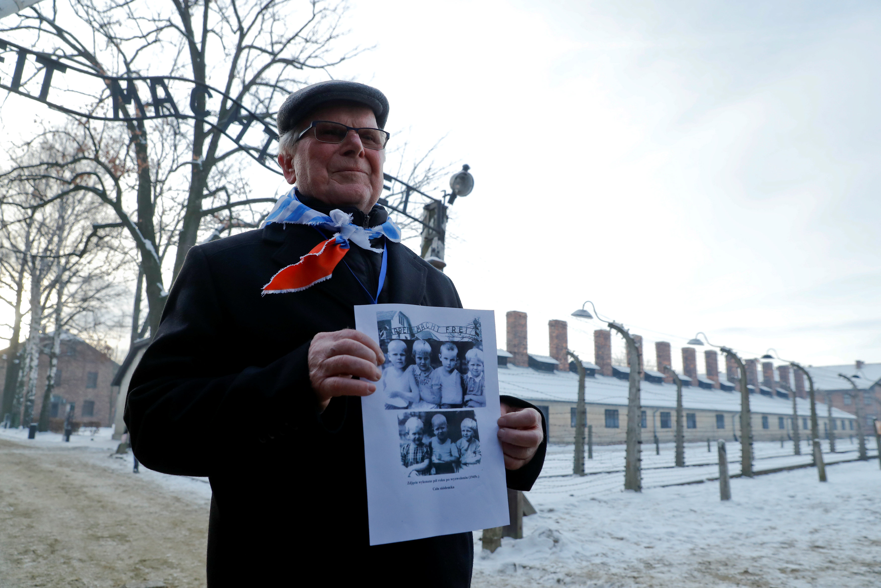 أحد الناجين يحمل صورا لعدد من ضحايا المعتقل
