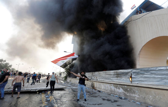 متظاهر-يرفع-علم-بلاده-بينما-يحرق-مبانيها