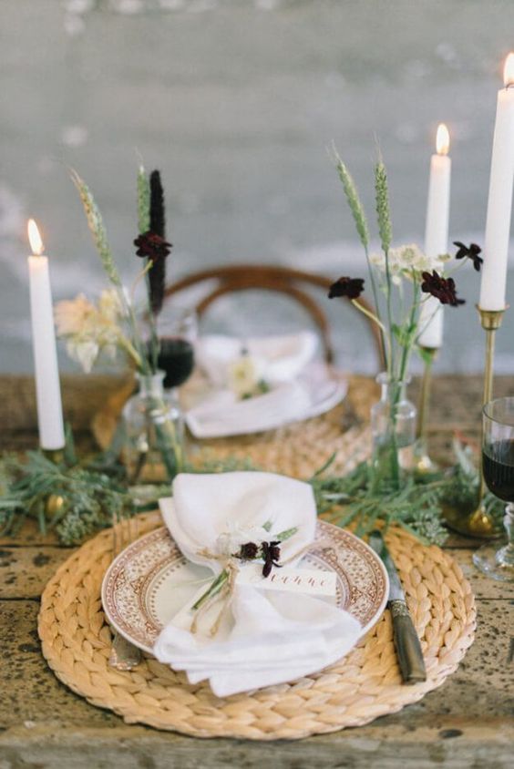 طاولة بسيطة مع المفارش المنسوجة ، والشموع  الطويلة ، ومساحات خضراء