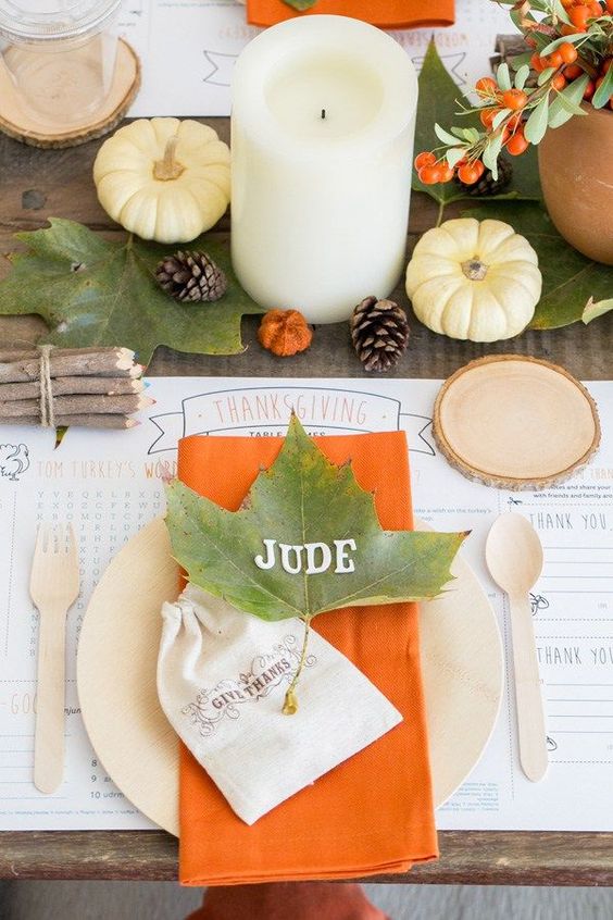 طاولة بسيطة مع أوراق الخريف والتوت والقرع والشموع عمود ولمسات من اللون البرتقالي