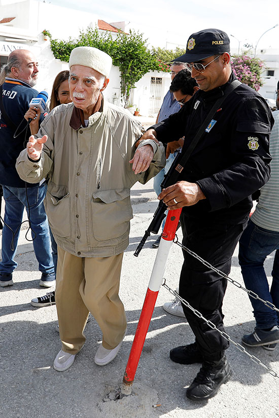 رجل يساعده أحد أفراد الشرطة أثناء وصوله للإدلاء بصوته