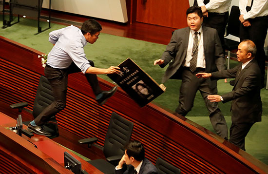 أحد أعضاء المجلس التشريعي يقفز على الأثاث وهو يحاول اتباع الرئيس التنفيذي لهونج