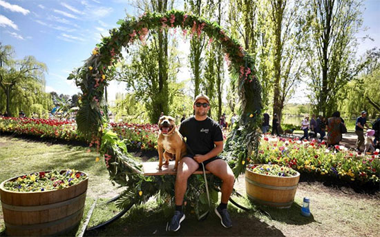 يلتقط صورة مع كلبه وسط الزهور