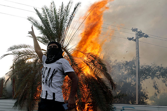 محتج يقف بجوار شجره محترقة