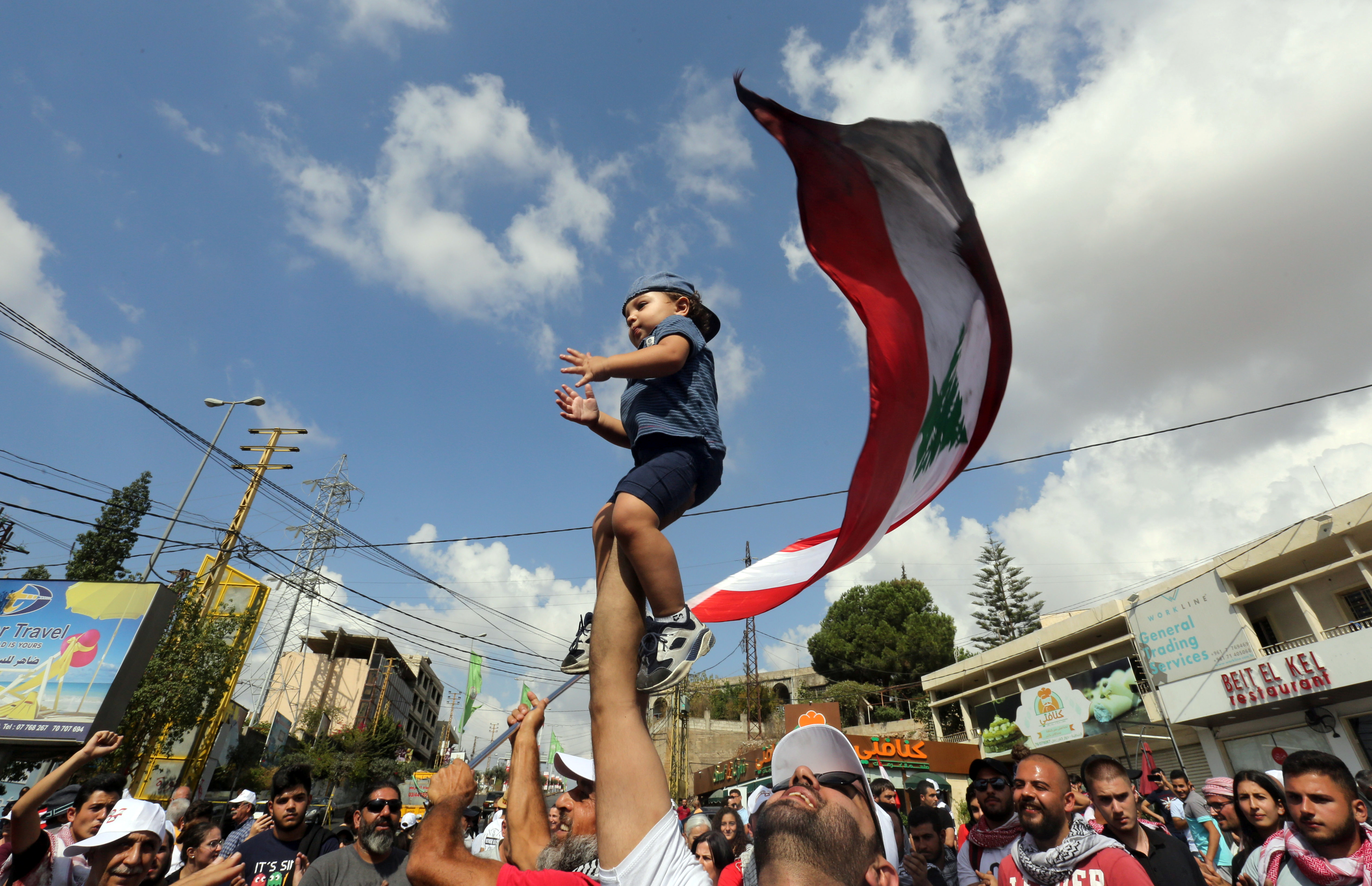 رجل يرفع طفلاً بينما يهتف المتظاهرون
