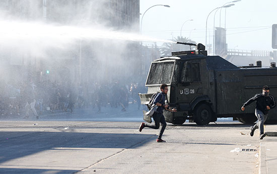 متظاهر يهرب أمام مدرعة للشرطة فى تشيلى