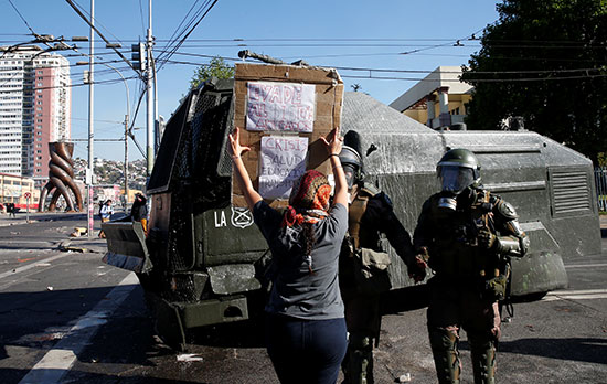 متظاهرة ترفع لافتة احتجاجية فى وجه قوات تشيلى