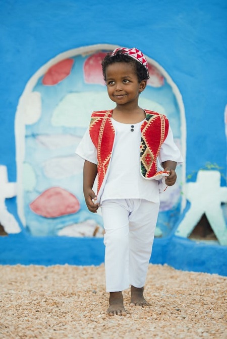 صورة للطفل مع البيوت النوبية الملونة 