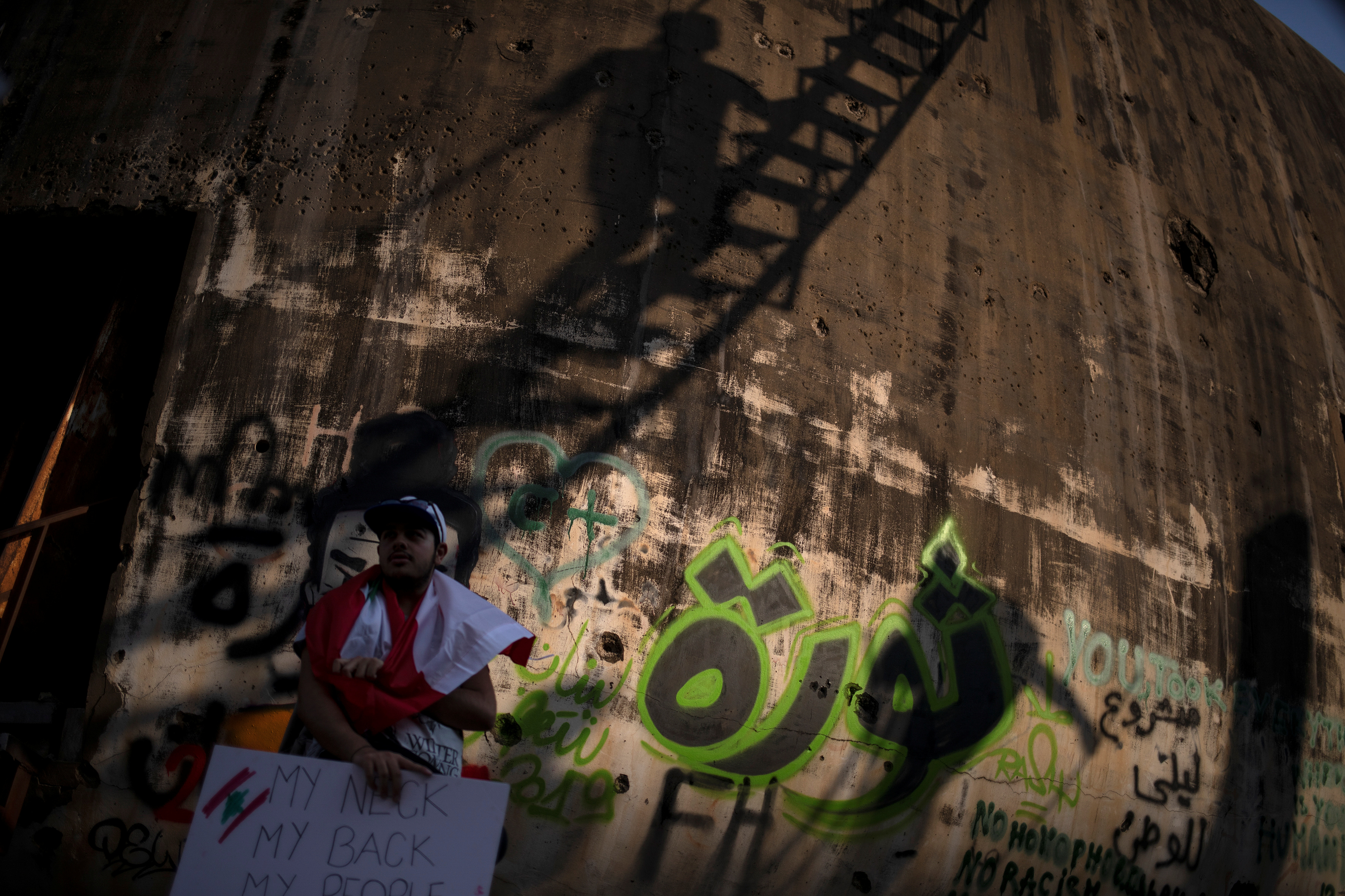 مواطن لبنانى يقف امام حائط مكتوب علية كلمة ثورة