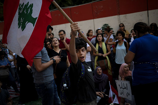 طفل مشارك فى المظاهرات يلوح بالعلم اللبنانى
